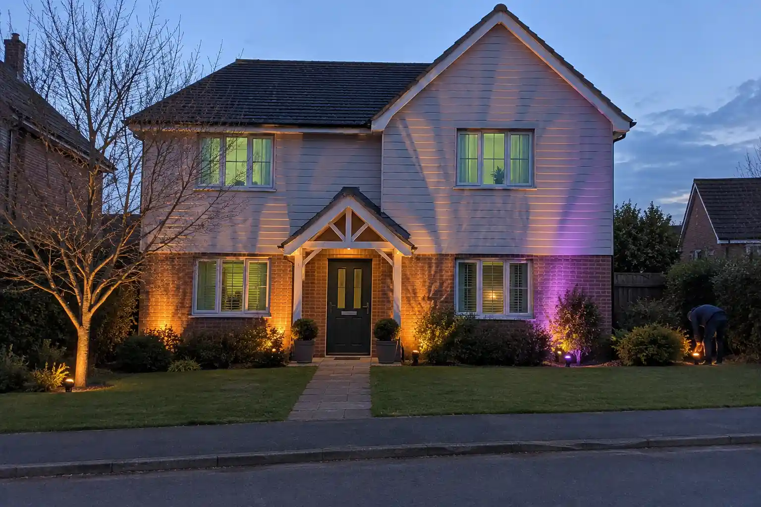 Villa i skymning med orange och lila strålkastare, ett exempel på filmisk halloweenmakeover med smart belysning